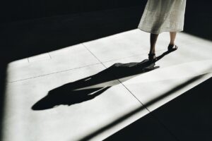 Photo of a woman walking away and casting a shadow.