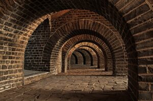 Photo of curved brick vaulted cellar with many arches.